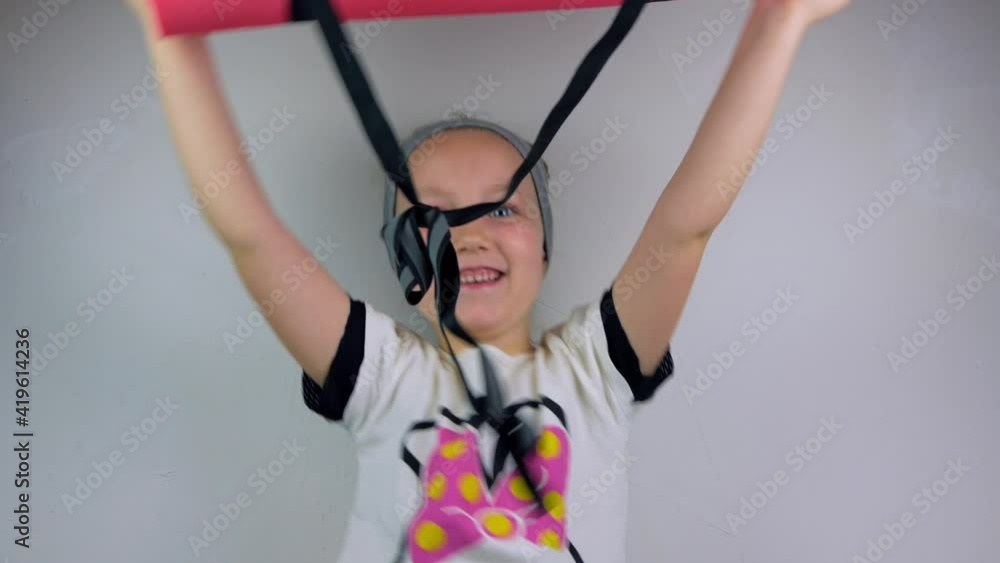 Little girl with pink yoga mat on gray background. Yoga for children flexibility practicing mental health active lifestyle, sport fitness class. Wellness online stretching training at home. New normal Little girl with pink yoga mat on gray background. Yoga for children flexibility practicing mental health active lifestyle, sport fitness class. Wellness online stretching training at home. New normal