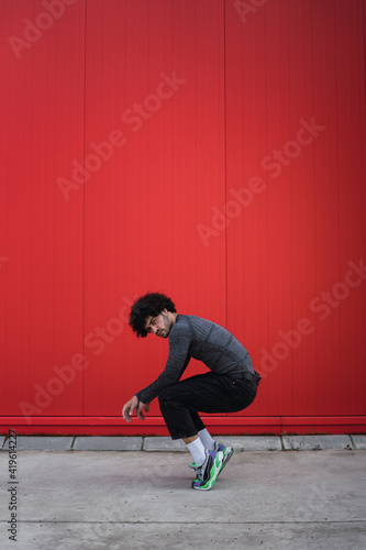 Chico joven bailando y sonriendo delante de una pared roja © MiguelAngelJunquera