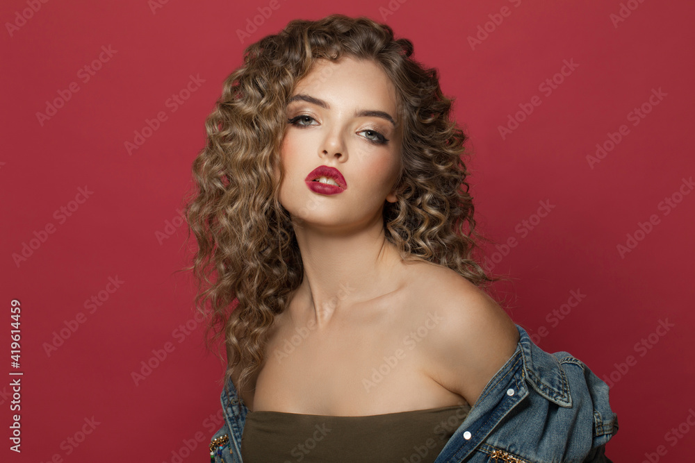 Fashionable woman fashion model with curly hair on red background