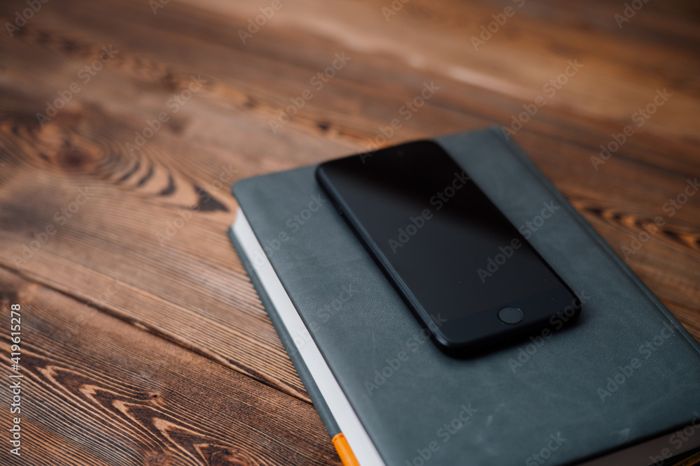 mobile phone and book with cover on wooden background mobile phone and book with cover on wooden background