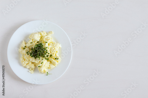 Scrambled eggs with microgreens on a white plate. Copy space