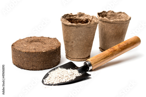 Garden shovel, craftsmen with mineral nitrogen fertilizer, peat pots, peat tablet close-up on a white background. The concept of farming, growing plants on domestic beds. home garden