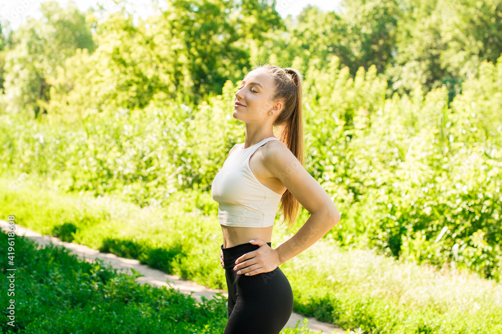 A beautiful girl in a sports uniform is smiling. She trained in nature. On the background green grass A beautiful girl in a sports uniform is smiling. She trained in nature. On the background green grass