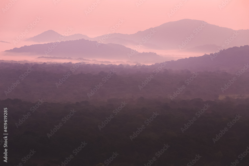 Countryside landscape view from Pidurangala Hill of misty rolling hills in the jungle of Sri Lanka at sunset or sunrise.
