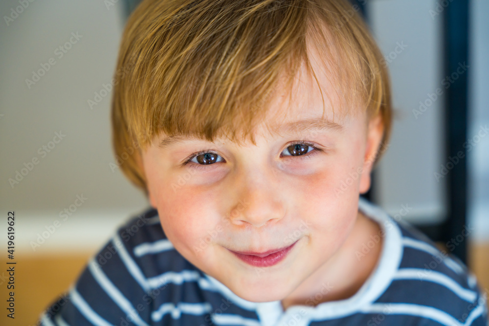 Close up portrait of a toddler boy of three years old indoor. Happy child wearing striped t shirt looking at the camera smiling with pleasure Close up portrait of a toddler boy of three years old indoor. Happy child wearing striped t shirt looking at the camera smiling with pleasure