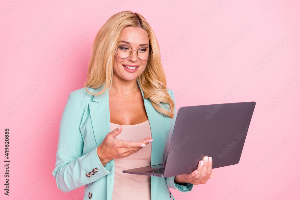 Photo of young happy positive businesswoman explaining presentation in laptop isolated on pink color background Photo of young happy positive businesswoman explaining presentation in laptop isolated on pink color background