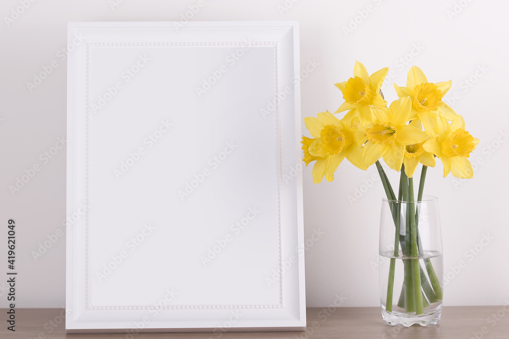 Breakfast still life., empty picture frame mockup on wooden desk, table. Vase with daffodils branches. Elegant working space, home office concept. Scandinavian interior design Breakfast still life., empty picture frame mockup on wooden desk, table. Vase with daffodils branches. Elegant working space, home office concept. Scandinavian interior design