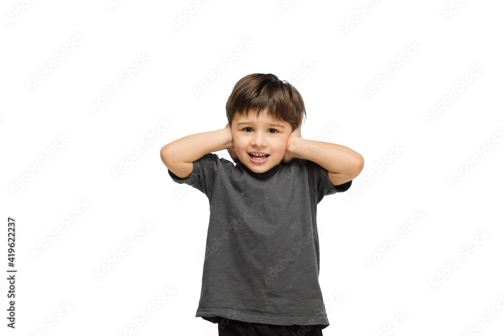 Closing ears. Happy, smiley little caucasian boy isolated on white studio background with copyspace for ad. Looks happy, cheerful. Childhood, education, human emotions, facial expression concept. Closing ears. Happy, smiley little caucasian boy isolated on white studio background with copyspace for ad. Looks happy, cheerful. Childhood, education, human emotions, facial expression concept.