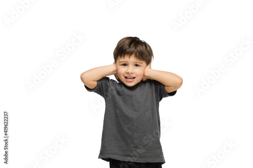 Closing ears. Happy, smiley little caucasian boy isolated on white studio background with copyspace for ad. Looks happy, cheerful. Childhood, education, human emotions, facial expression concept.