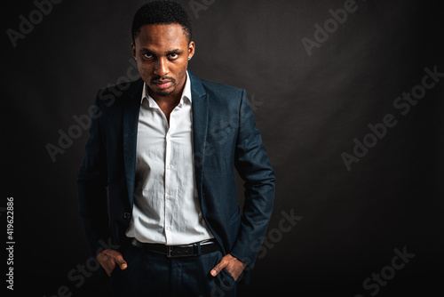 portrait of attractive, beautiful, serious and stylish professional African American businesswoman in dark suit and white shirt isolated on dark background. Low key. Selective focus	