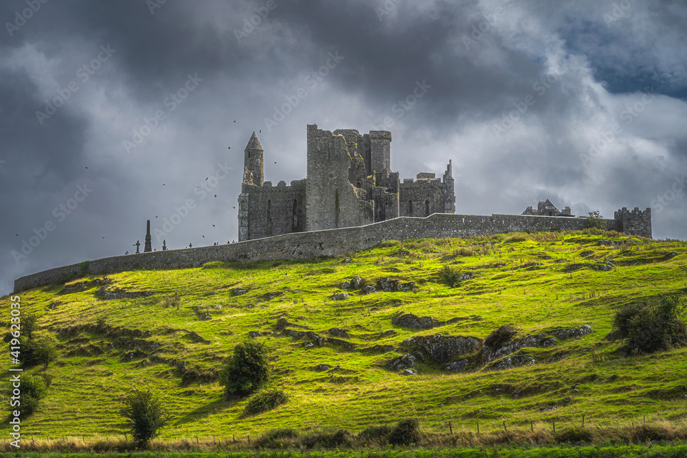 Majestic castle, Rock of Cashel, with flying crows around the tower and dramatic dark storm clouds in background, County Tipperary, Ireland Majestic castle, Rock of Cashel, with flying crows around the tower and dramatic dark storm clouds in background, County Tipperary, Ireland
