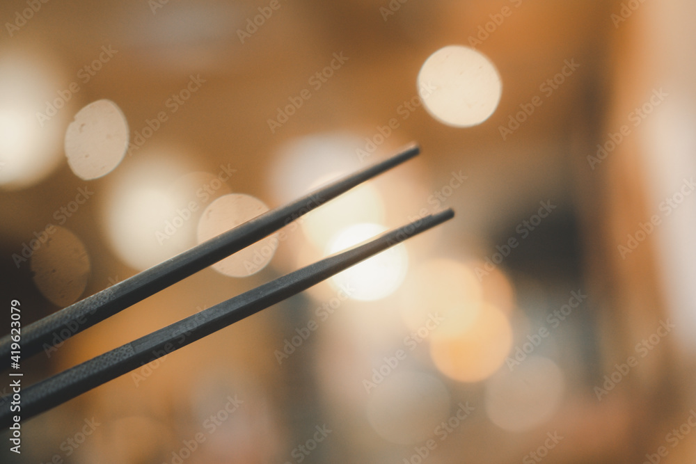 Two black chopsticks on a orange bokeh Two black chopsticks on a orange bokeh