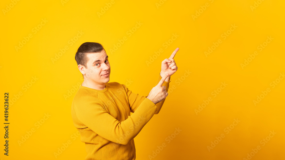 Banner. Young handsome man wearing casual sweater over yellow background smiling and looking at the camera pointing with two hands and fingers to the side. Banner. Young handsome man wearing casual sweater over yellow background smiling and looking at the camera pointing with two hands and fingers to the side.