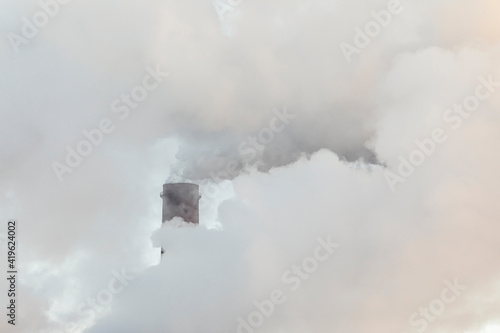A industrial chimney in the clouds of steam. Sunny winter day.