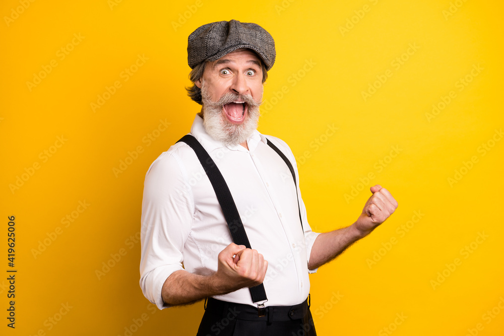 Photo of aged man excited happy positive smile rejoice win victory fists hand isolated over yellow color background