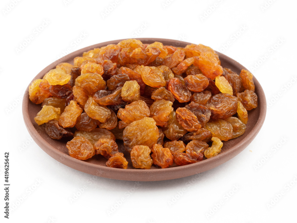 Raisins in clay plate on white. Healthy eating concept Raisins in clay plate on white. Healthy eating concept