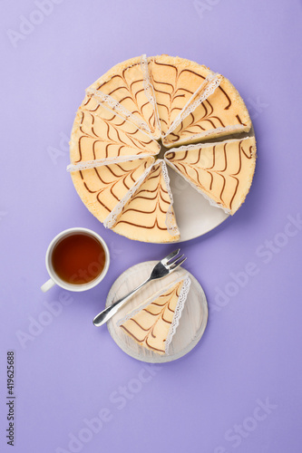 A few pieces of cheesecake on a plate with a cup of tea on a colored background. A delicious dessert for a birthday and holiday.