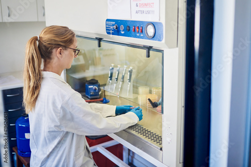 Φωτογραφία Female lab technician working with samples inside a biosafety cabinet
