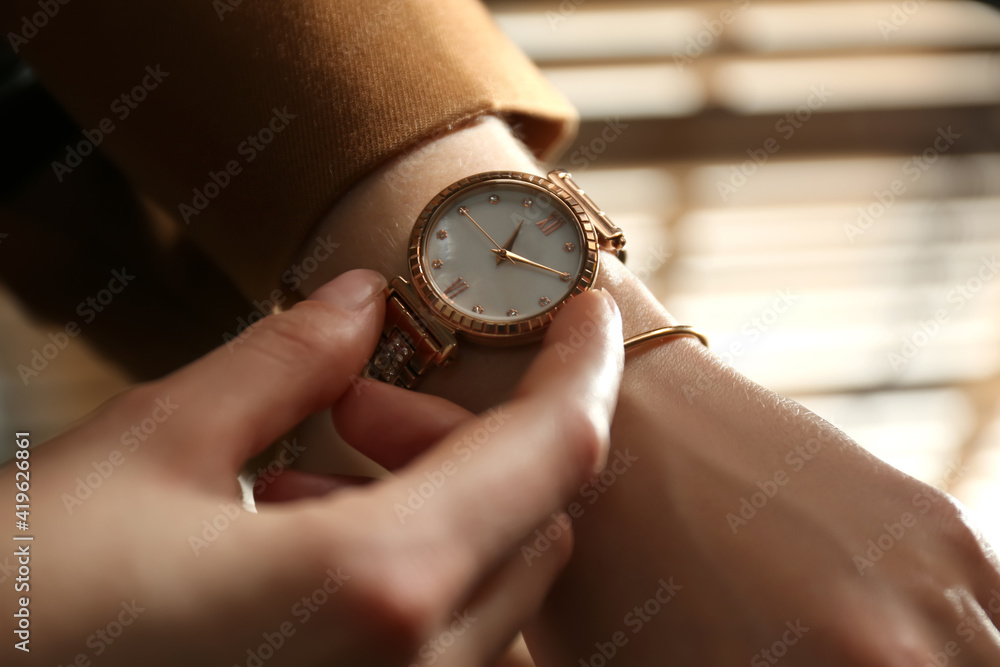 Woman wearing luxury wristwatch indoors, closeup of hand Woman wearing luxury wristwatch indoors, closeup of hand