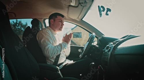 The man in the car sneezes heavily from dust, allergies.