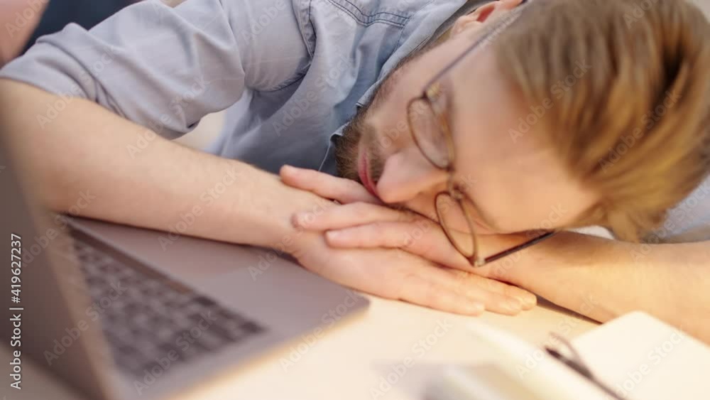 Male company manager sleeping on the table in front of laptop, project deadline Male company manager sleeping on the table in front of laptop, project deadline