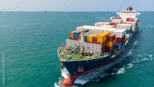 Aerial side view of smart cargo ship carrying container from custom container depot go to ocean concept freight shipping by ship service on blue sky background.  forwarder mast