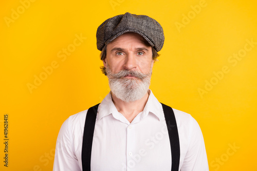 Photo portrait of bearded man wearing grey cap shirt suspenders isolated on bright yellow color background