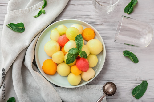 Plate with sweet fruit balls on wooden background