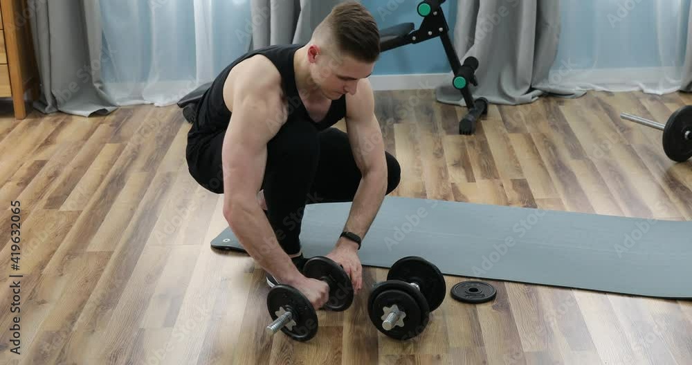 Man hand adding weights from a dumbbell in the gym. Adding Weights To A