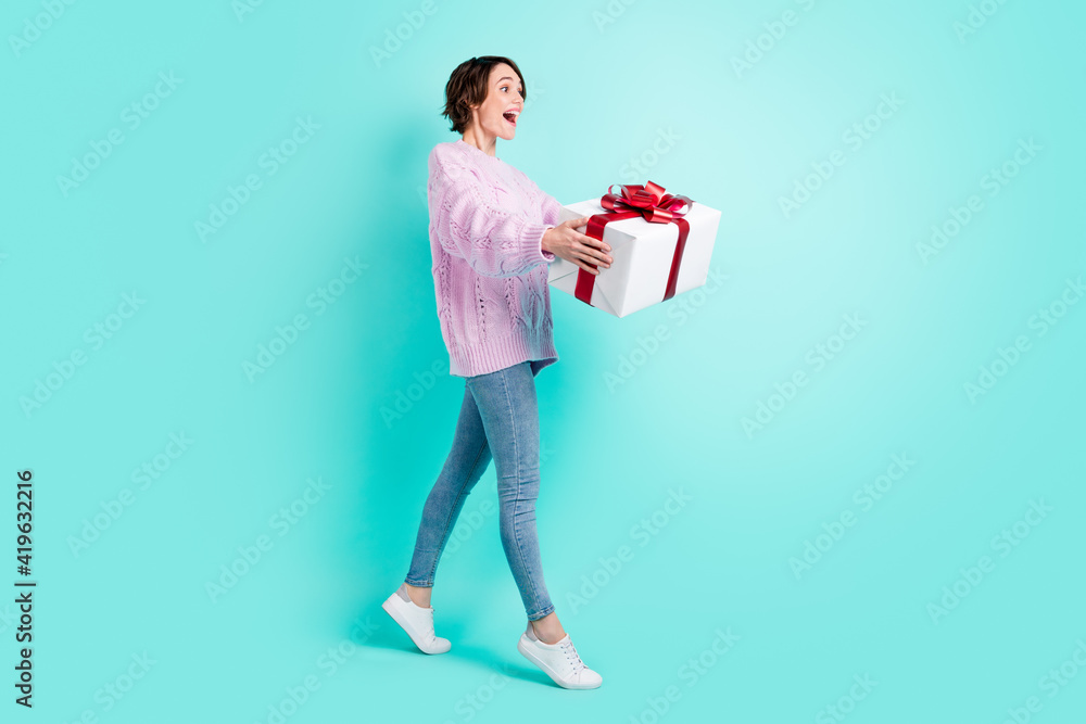 Full length photo of adorable funky woman wear violet sweater present looking empty space isolated turquoise color background Full length photo of adorable funky woman wear violet sweater present looking empty space isolated turquoise color background