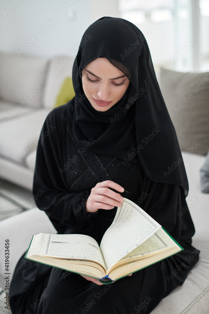 Portrait of young muslim woman reading Quran in modern home Portrait of young muslim woman reading Quran in modern home