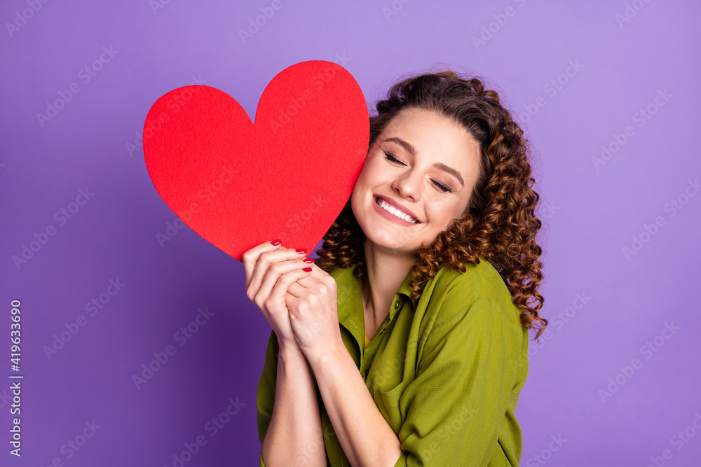 Photo of young happy cheerful smiling positive good mood girl hold big red heart isolated on violet color background Photo of young happy cheerful smiling positive good mood girl hold big red heart isolated on violet color background