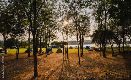 Tourist tent camping under the tree forest near the lake and beautiful sunlight.