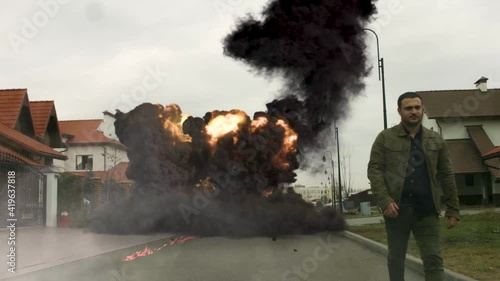 cool guy walks in the background of a car explosion