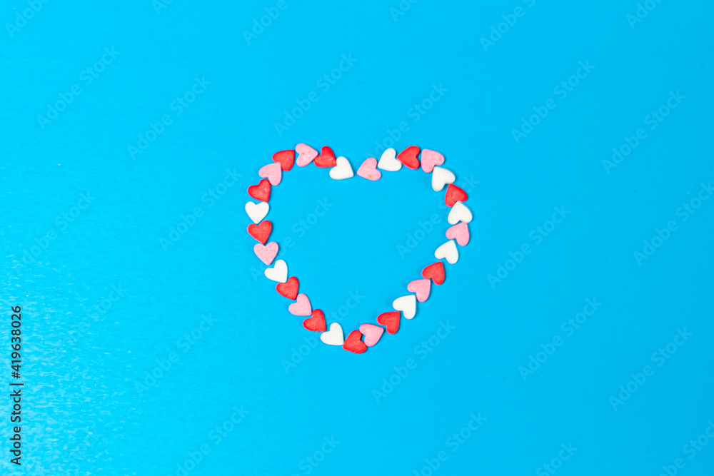 Fototapeta premium small white, pink and red hearts forming a bigger heart on blue background