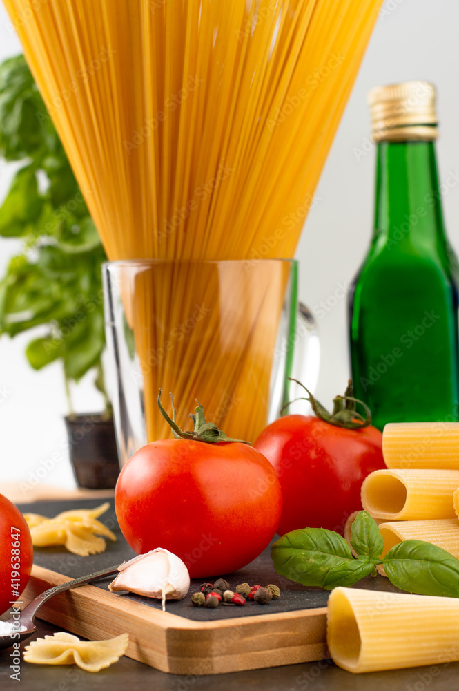 Blurred image in the foreground of a tomato, sprigs of basil, garlic, in the background spaghetti, olive oil. Blurred image in the foreground of a tomato, sprigs of basil, garlic, in the background spaghetti, olive oil.