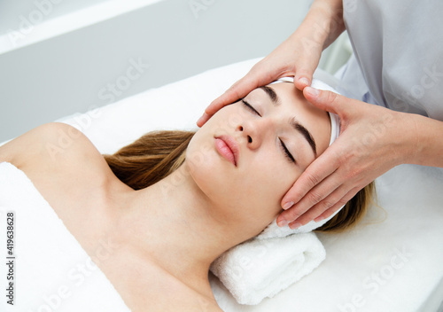 Beautician massaging woman's face. Attractive girl having facial treatment and massage.