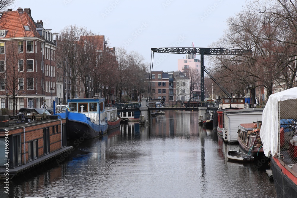 Amsterdam Canal View with Boats, Iron Bridge and a Man on a Bike
