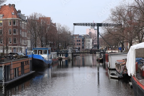 Amsterdam Canal View with Boats, Iron Bridge and a Man on a Bike photo