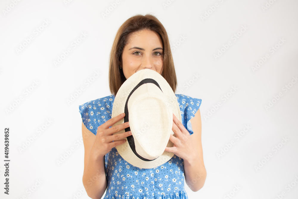 Beautiful young woman laughing woman in blue dress and straw hat looking happy over white background Beautiful young woman laughing woman in blue dress and straw hat looking happy over white background