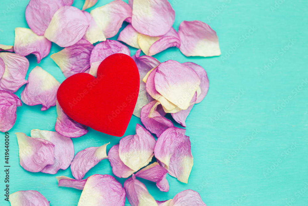 Fototapeta premium Closeup red heart on pink rose leaves on blue background, vintage tone style, love and romance concept, valentine card background idea