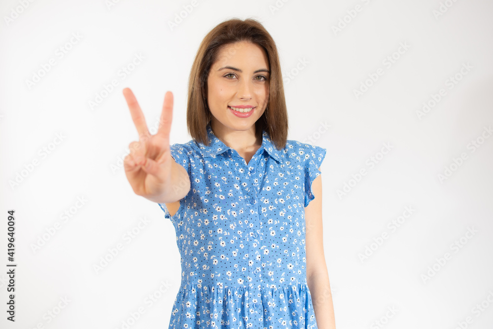 Young pretty woman isolated showing victory sign and smiling broadly. Young pretty woman isolated showing victory sign and smiling broadly.