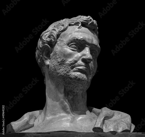Head detail of the ancient man sculpture. Stone face isolated on black background. Antique marble statue of mythical hero character photo