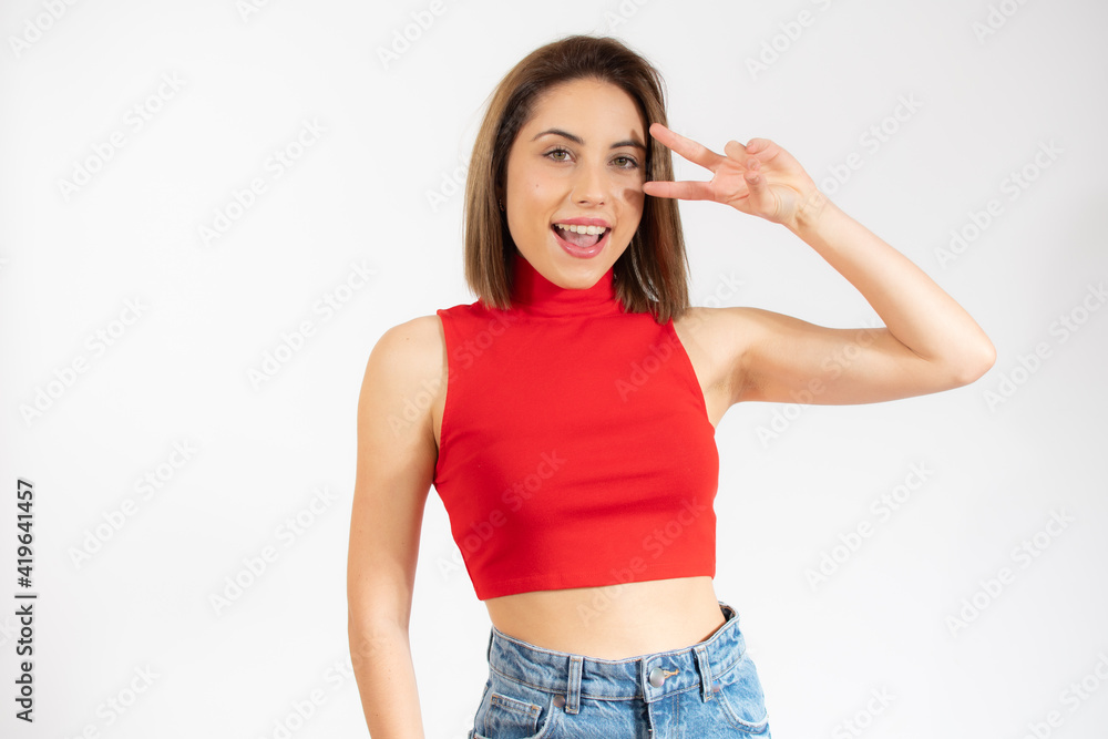 Young pretty woman isolated showing victory sign and smiling broadly. Young pretty woman isolated showing victory sign and smiling broadly.