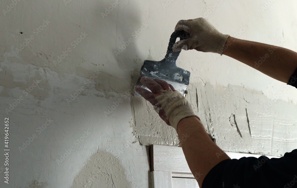 plastering the wall above the installed door frame with a trowel and