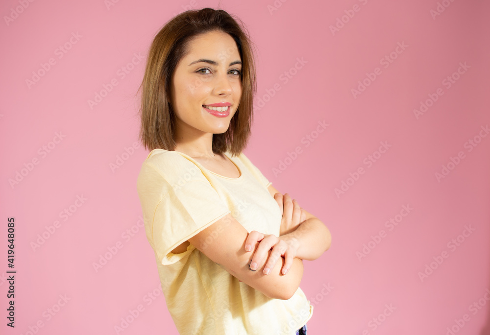 Portrait of a smiling young woman standing with arms folded isolated over pink background Portrait of a smiling young woman standing with arms folded isolated over pink background