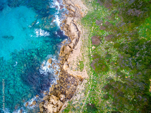 Green meadow and blue sea seen from above in Alghero coastline