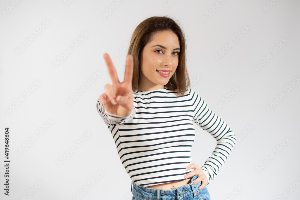 Young pretty woman isolated showing victory sign and smiling broadly. Young pretty woman isolated showing victory sign and smiling broadly.
