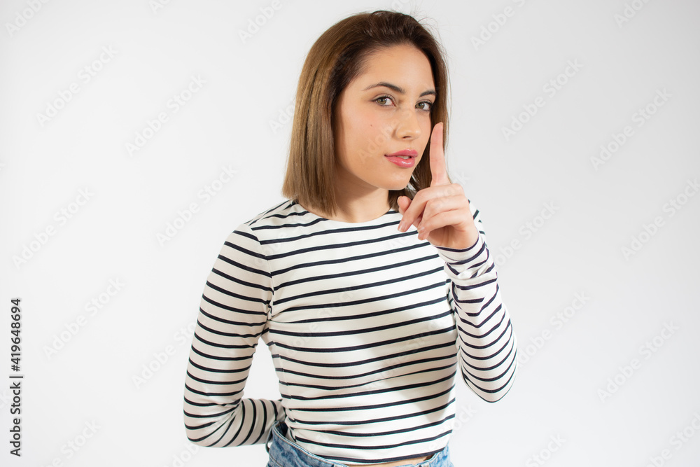 Portrait of beautiful and young woman standing over isolated white background asking to be quiet with finger on lips. Silence and secret concept. Portrait of beautiful and young woman standing over isolated white background asking to be quiet with finger on lips. Silence and secret concept.