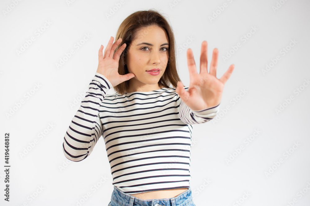 Young beautiful woman wearing casual striped t-shirt over isolated white background Moving away hands palms showing refusal and denial with afraid and disgusting expression. Stop and forbidden.